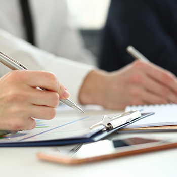 Office workers writing on clipboards in a meeting