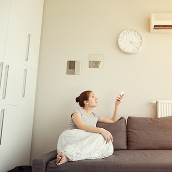 Woman in sitting room operating air conditiing unit